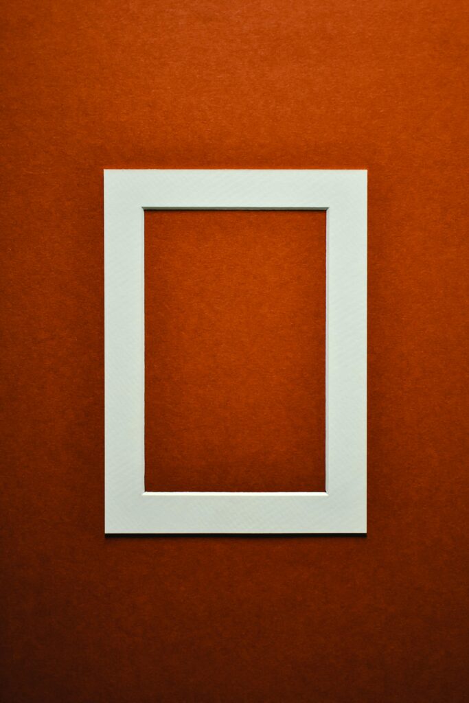 Minimalist white picture frame against a textured red background.